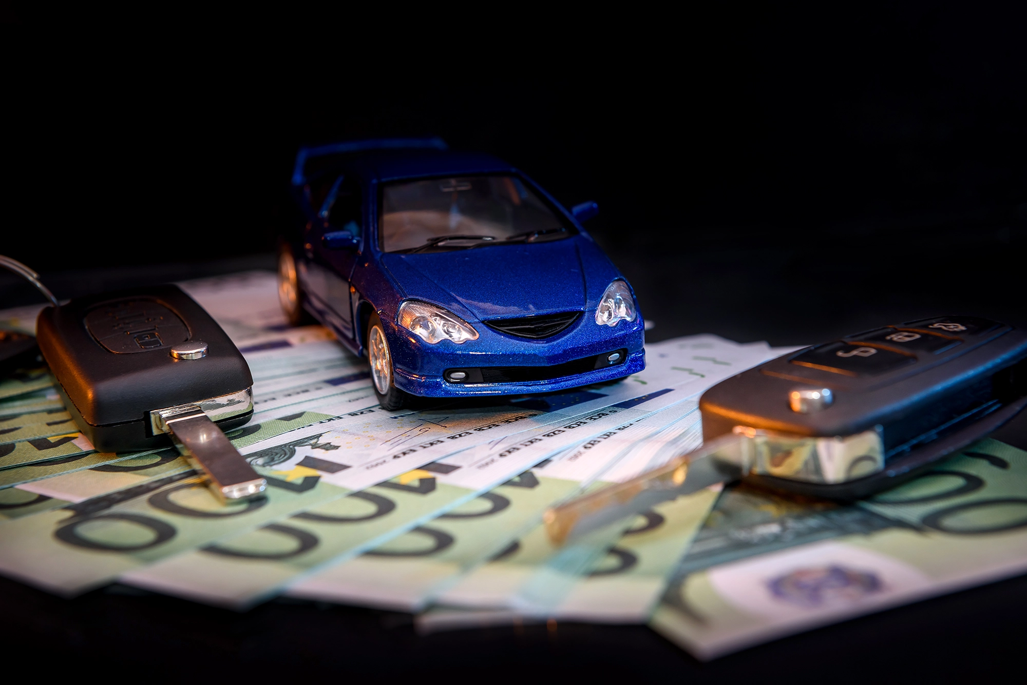 Niebieski model samochodu, kluczyki oraz banknoty euro – symbol zakupu i rejestracji pojazdu.